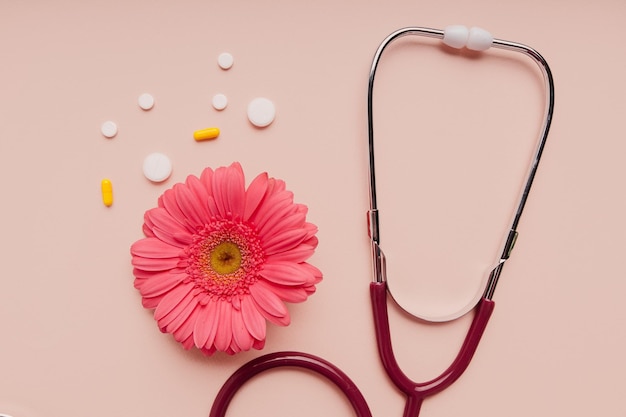 Stéthoscope et fleur rose avec gros plan de pilules Concept de diagnostic et de traitement Soins de santé de la femme