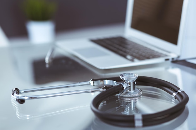 Stéthoscope, formulaire médical de prescription allongé sur une table en verre avec ordinateur portable. Concept de médecine ou de pharmacie. Outils médicaux à la table de travail du médecin.