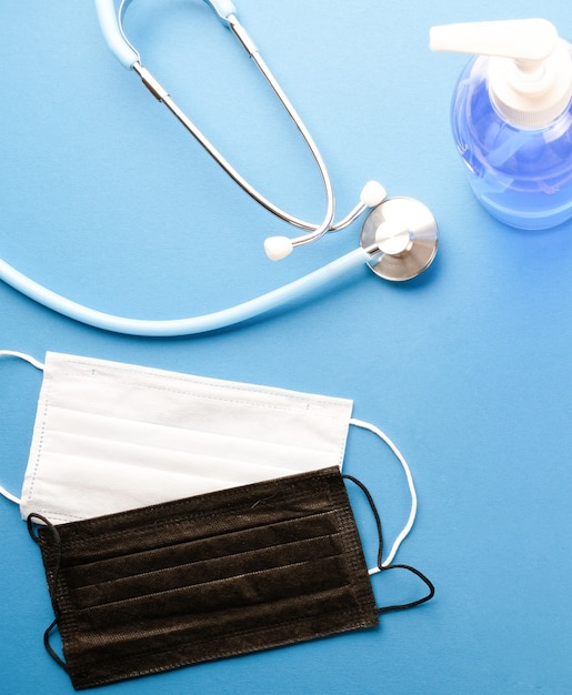 Stéthoscope, masques médicaux et gel antibactérien sur une table bleue