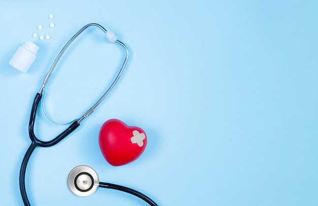 Stéthoscope de médecine, bouteille de pilules et coeur rouge avec vue de dessus en plâtre sur table de cardiologue