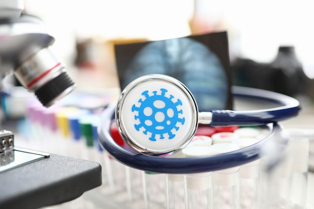 Photo stéthoscope médical couché sur un ensemble de flacons en gros plan de laboratoire scientifique. développement de vaccins et concept de problème de médicament