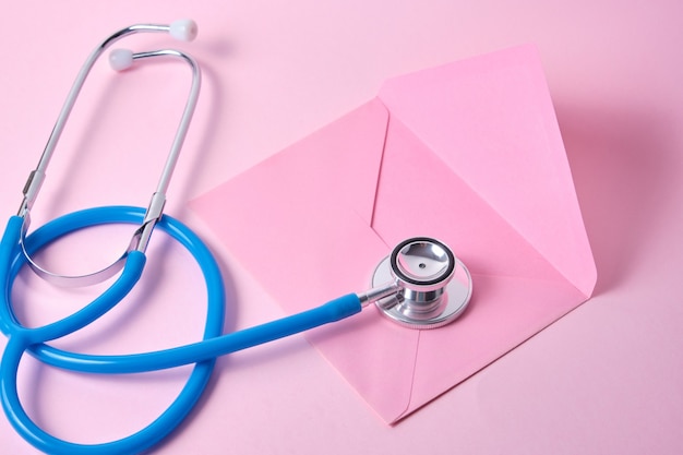 Stéthoscope et plusieurs enveloppes colorées le jour du médecin de surface rose