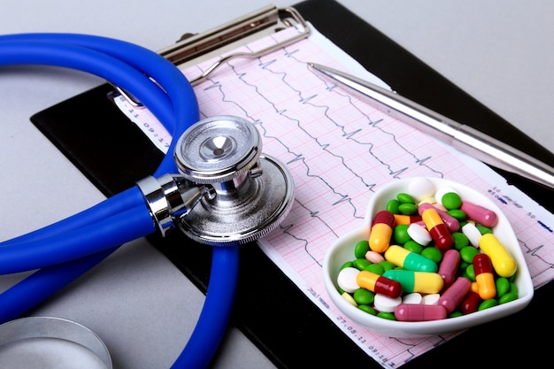 Stéthoscope, prescription RX et pilules et capsules d’assortiments colorés sur assiette.