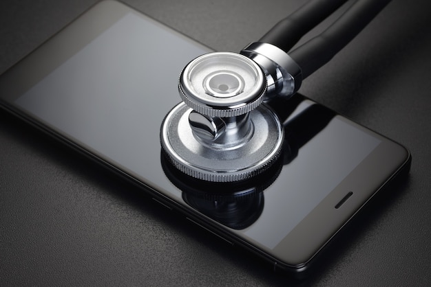 Stéthoscope et smartphone sur fond noir