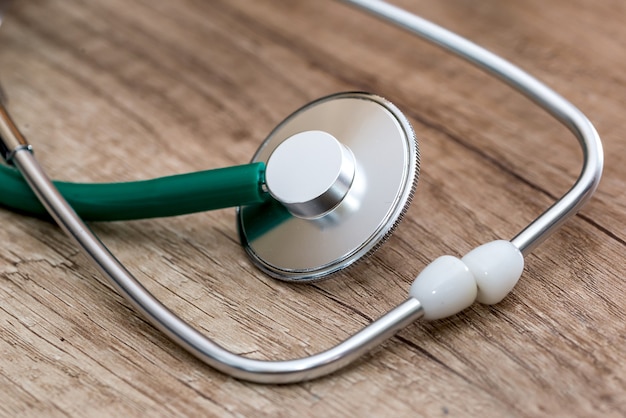 Un stéthoscope vert est allongé sur une table en bois