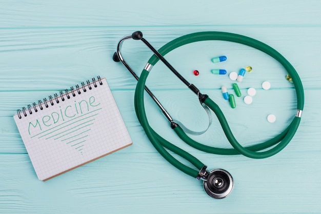 Stéthoscope vert et pilules sur fond bleu. Médecine sur ordinateur portable. Concept de soins de santé.