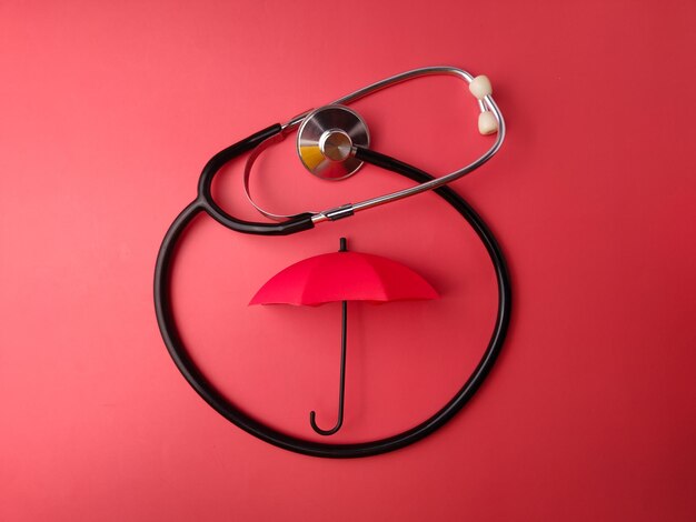 Stéthoscope vue de dessus et parapluie rouge sur fond rouge