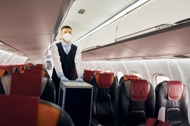 Steward en uniforme se promène avec des bagages à l'intérieur de l'avion