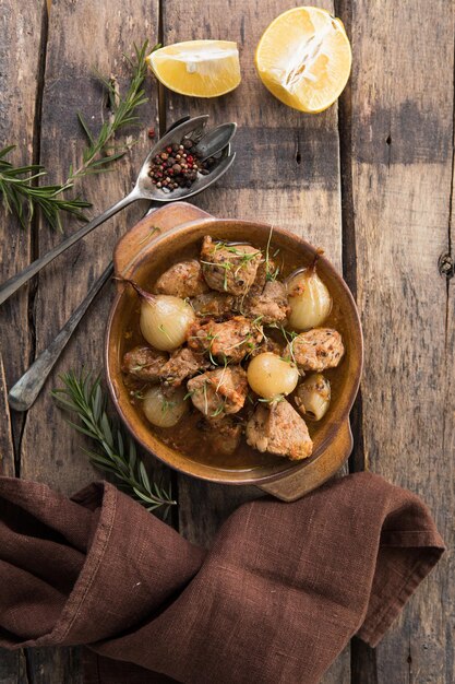 Stifado - délicieux ragoût de boeuf méditerranéen avec bulbes d'oignons, cannelle et épices dans une casserole, sur une table en bois noir, vue d'en haut, gros plan