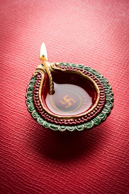 Stock photo de belle diwali diya avec des cadeaux et des fleurs, sur fond décoratif, éclairage de mauvaise humeur et mise au point sélective