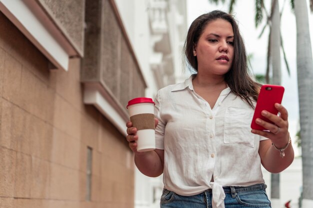 Stock photo d'une belle jeune femme marchant dans la rue et utilisant son téléphone.