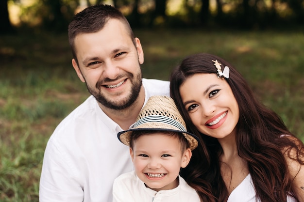 Photo stock photo headshot d'une belle famille caucasienne de mère, père et leur fils souriant joyeusement à la caméra dans le parc le jour d'été.