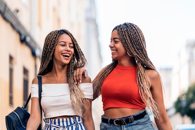 Stock photo de jolies soeurs afro-américaines avec des tresses fraîches marchant dans la rue.