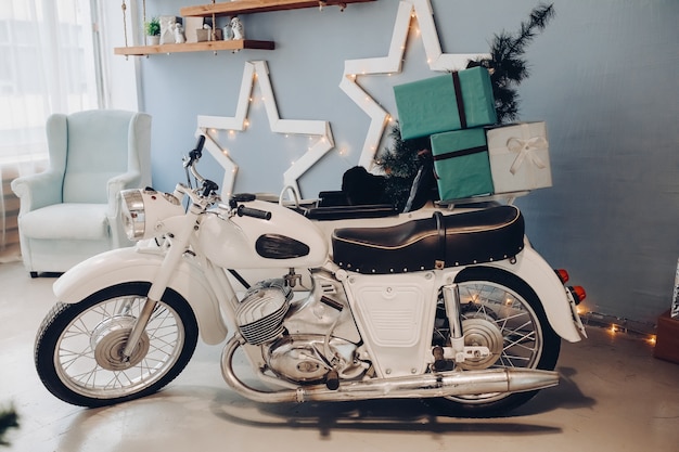 Stock photo de moto blanche avec arbre de Noël miniature et cadeaux de Noël enveloppés dans le berceau. Intérieur atmosphérique pour le jour de Noël. Nouvel an 2020.