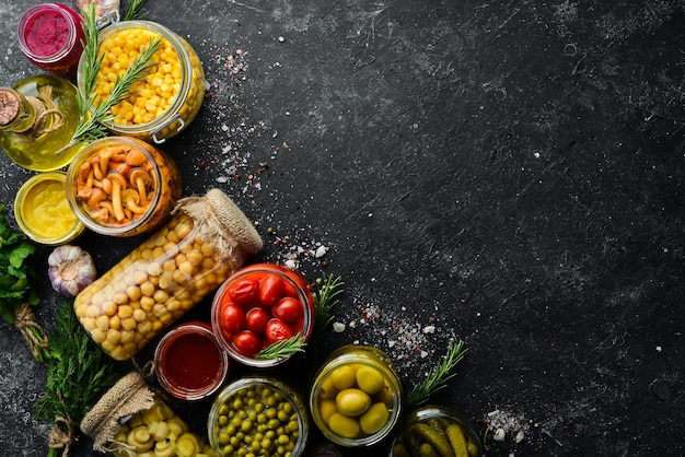 Stocks alimentaires dans des bocaux en verre Légumes marinés Sur fond noir Vue de dessus