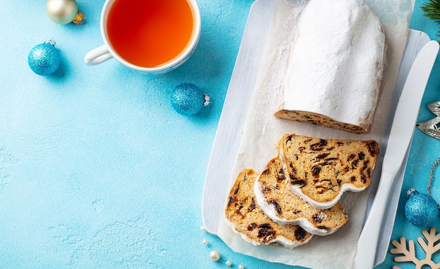 Stollen de Noël Dessert festif traditionnel allemand avec une tasse de thé Fond bleu Copier l'espace Vue de dessus