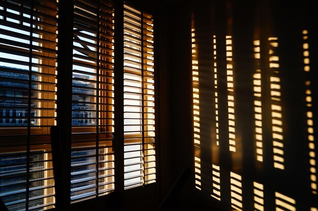 Des stores en bois avec un reflet rayé sur le mur