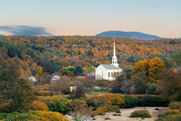 Photo stowe au coucher du soleil en automne avec un feuillage coloré et une église communautaire dans le vermont