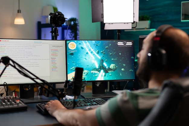 Streamer jouant à des jeux vidéo et parlant avec ses coéquipiers sur un chat ouvert en streaming. Cyber se produisant sur un ordinateur puissant dans une salle de jeux à domicile à l'aide d'équipements professionnels