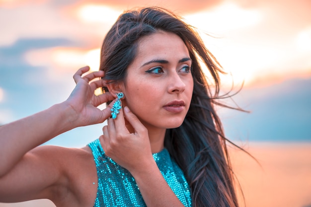 Street style, une jolie brune dans un magnifique coucher de soleil dans une robe moulante à sequins