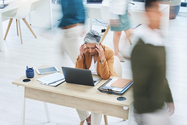 Stress au bureau occupé et femme âgée souffrant de crise de maux de tête ou de vertiges alors qu'elle travaille sur un ordinateur portable Chaos d'entreprise et dame PDG avec massage des tempes pour le brouillard cérébral de migraine ou le problème 404 ou l'anxiété