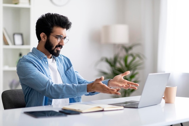 Le stress au travail en colère jeune pigiste indien ayant des problèmes avec un ordinateur portable