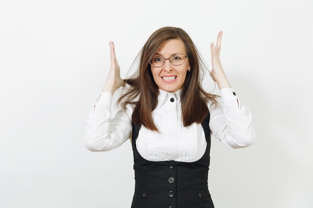 Stress choqué en colère jeune femme d'affaires caucasienne aux cheveux bruns en costume noir, chemise blanche et lunettes écartant les mains isolées sur le mur blanc