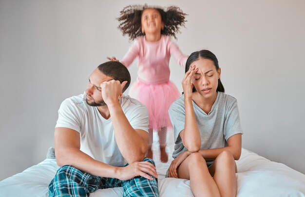 Photo stress divorce et couple avec un enfant sur le lit avec ses parents dans une dispute ou un désaccord fatigué rupture et jeune mère et père en colère avec une fille tdah sautant dans la chambre à leur domicile