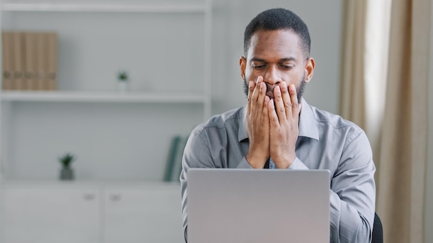 Stressé choqué afro-américain ethnique barbu adulte homme employé de bureau homme d'affaires avec ordinateur portable triste contrarié frustré de lire en ligne mauvaise nouvelle erreur service erreur échec problème commercial