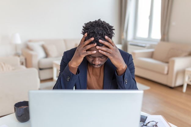 Stressé jeune homme d'affaires assis avec sa tête dans ses mains tout en travaillant à un bureau