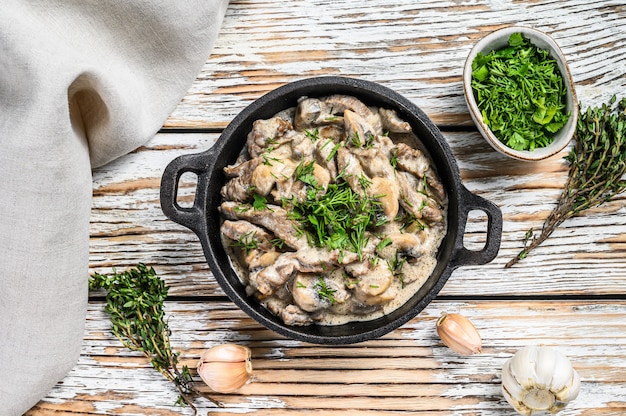 Stroganoff de boeuf aux champignons dans la poêle sur le tableau blanc.