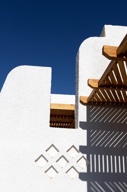 La structure en bois jette une ombre géométrique sur le mur blanc du bâtiment contre le ciel bleu clair Dahab Egypte