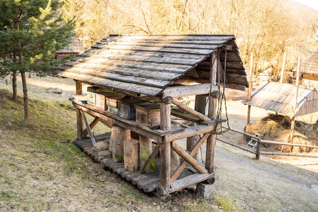 Une structure en bois avec un toit en bois se trouve sur une colline dans les bois.