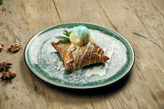 Strudel aux pommes avec glace à la vanille sur une plaque bleue sur une table en bois. Pâtisseries et desserts autrichiens populaires. Fermer