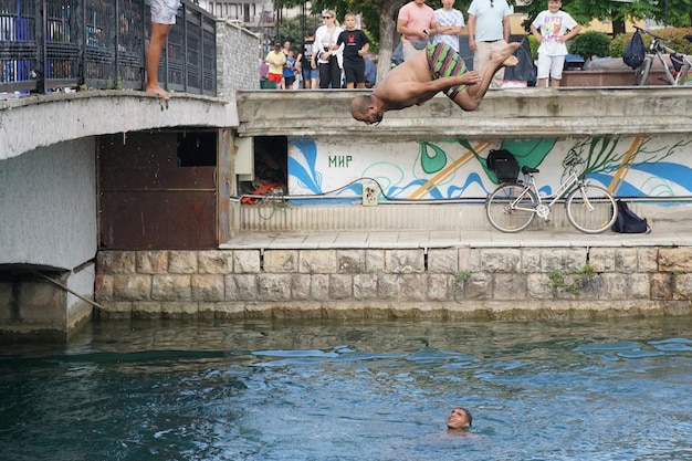 STRUGA MACÉDOINE 13 AOÛT 2023 les hommes sautent du pont dans l'eau d'une rivière Drim au centre-ville de Struga Macédoine