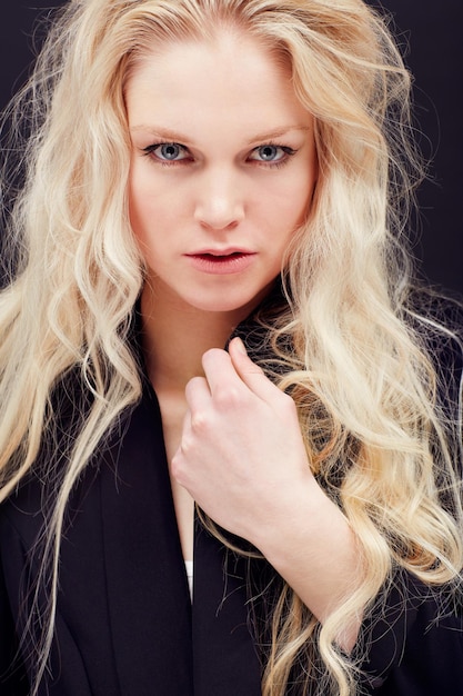 Studio de beauté et portrait de femme avec une coiffure blonde et un visage sérieux isolé sur fond noir Maquillage de soins de la peau et pose esthétique de luxe créative et mannequin sombre Allemagne