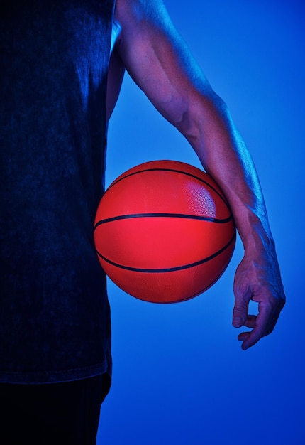 Studio de fitness et mains d'homme avec basket-ball pour l'entraînement de gymnase et le défi pour la compétition Club sportif et athlète professionnel avec exercice de balle et entraînement pour le jeu sur fond bleu