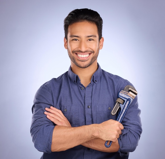 Studio d'homme et portrait avec outils ou clé pour travaux d'entretien ou de réparation de bricoleur avec sourire Heureux modèle asiatique sur fond bleu avec clé pour ingénieur mécanicien ou technicien