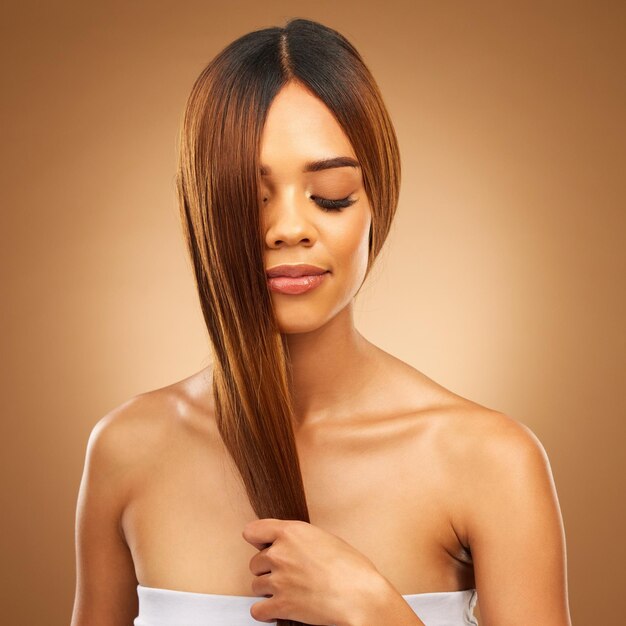 Photo studio de soins capillaires et femme aux cheveux en main forts avec une texture bronze et un éclat de salon maquette de modèle de bien-être et beauté spa coiffure droite saine avec produit à la kératine sur fond marron