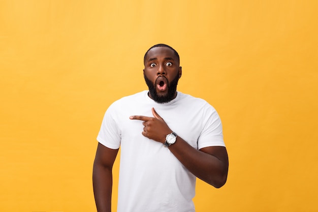 Stupéfié jeune hipster afro-américain portant un t-shirt blanc tenant par la main dans un geste surpris