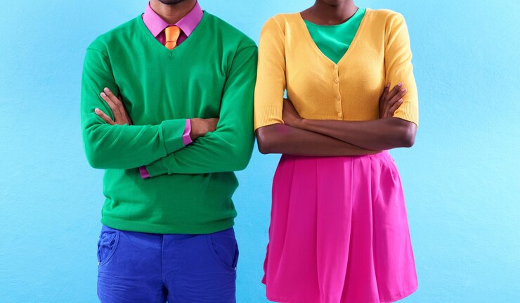 Photo style avec une attitude colorée prise de vue en studio recadrée de deux personnes élégamment habillées debout avec les bras croisés