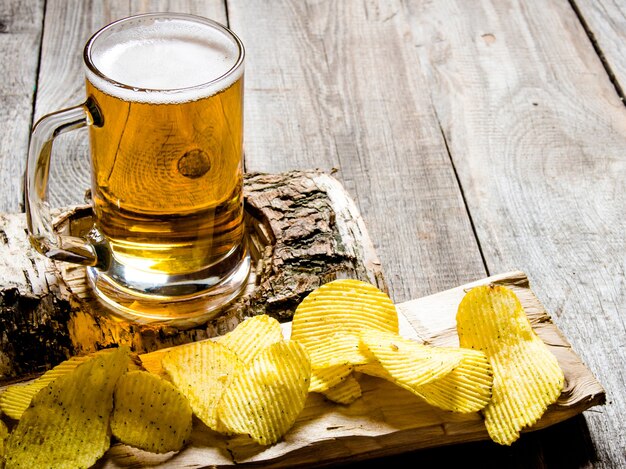 Le style de bière Verre de bière sur un stand de bouleau et frites sur fond de bois