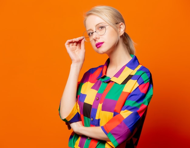 Style blonde en chemise des années 90 et lunettes sur orange