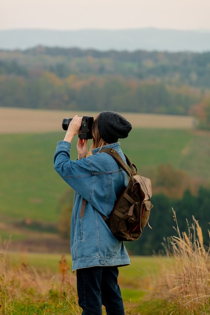 Style femme avec appareil photo et sac à dos à la campagne avec les montagnes