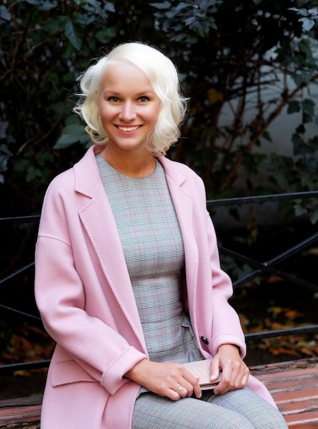 Style femme blonde assise sur le banc jour d'automne