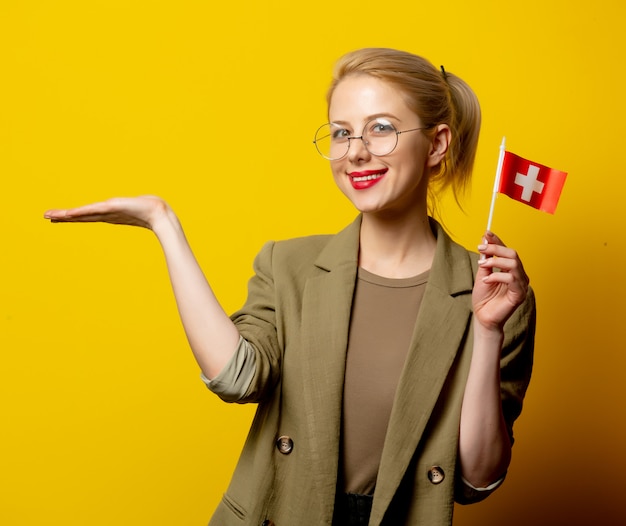 Style femme blonde en veste avec drapeau suisse sur jaune