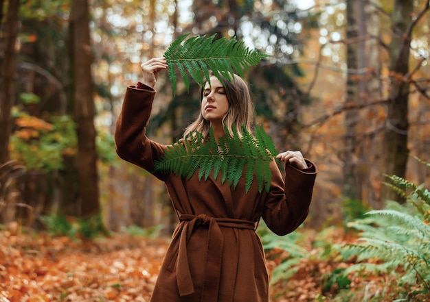 Style femme avec branche de fougère dans une forêt d'automne