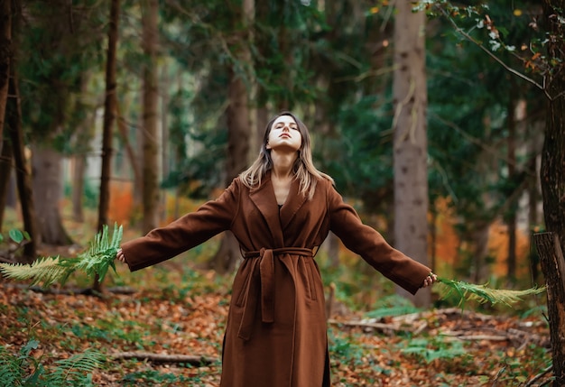 Style femme avec branche de fougère dans une forêt d'automne