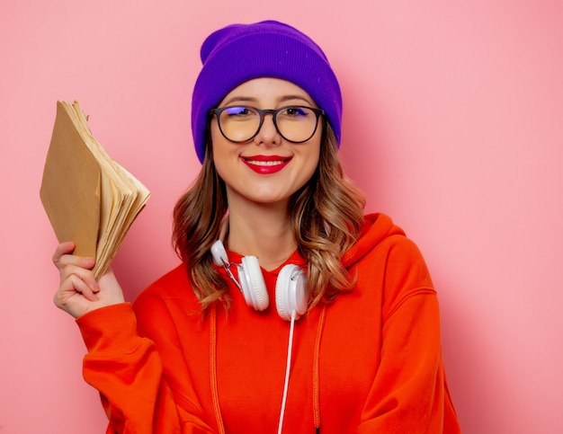 Style femme avec des écouteurs et des livres sur le mur rose