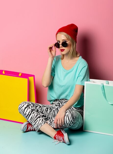 Style femme à lunettes de soleil avec des sacs à provisions sur mur rose